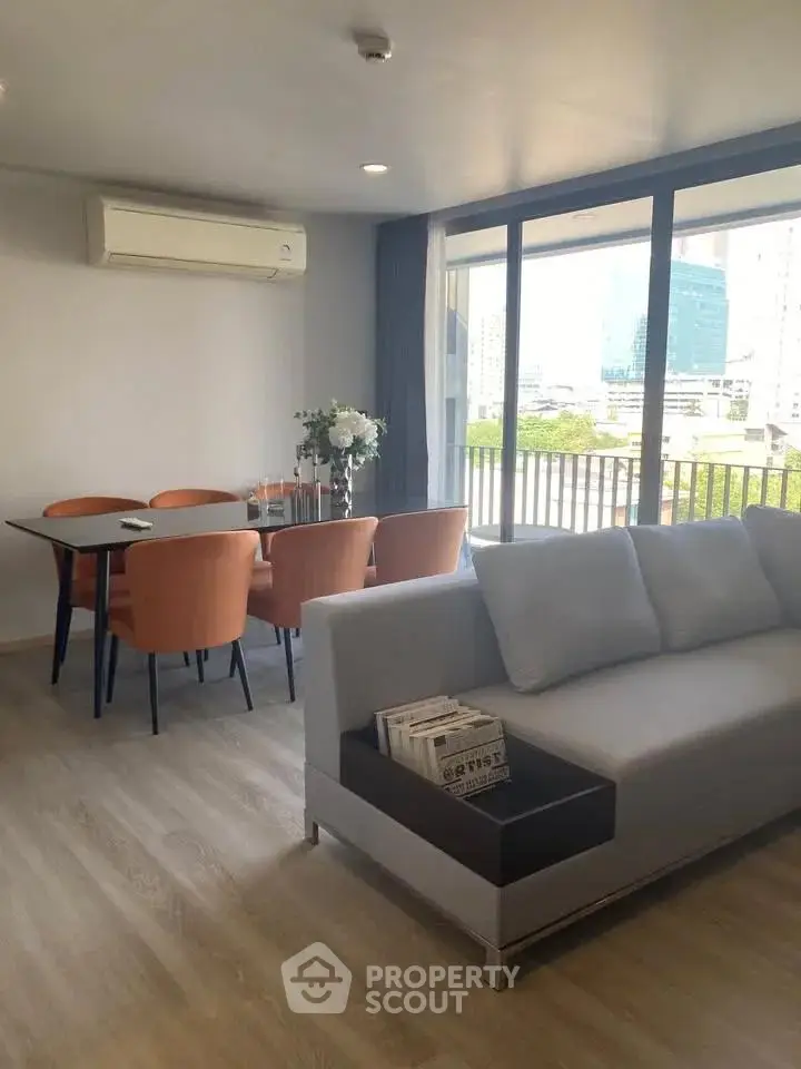 Spacious modern living room with large windows and city view, featuring stylish furniture and elegant decor.