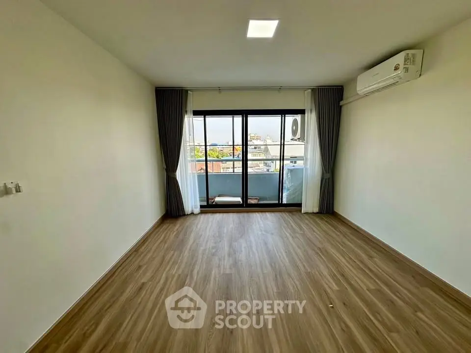 Spacious living room with wooden flooring and balcony view in modern apartment.