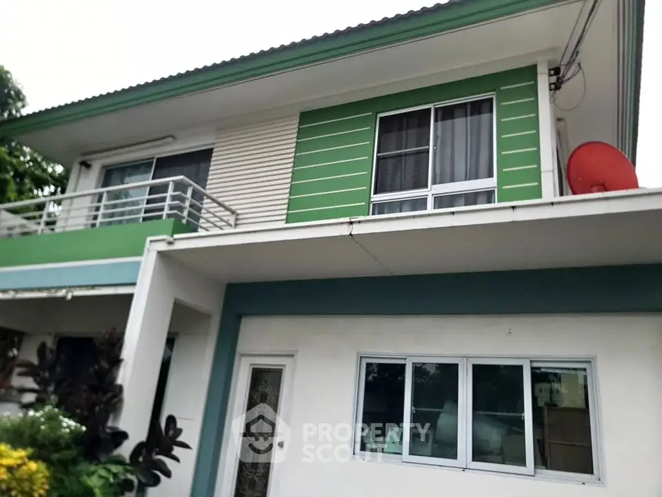 Charming two-story house with green accents and balcony, ideal for family living.