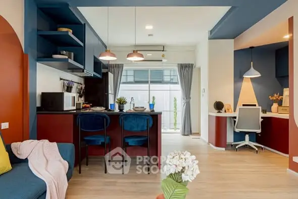 Stylish open-plan living room with modern kitchen and cozy workspace, featuring vibrant colors and contemporary design.