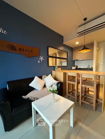 Charming beach-themed living room with cozy seating and modern kitchen bar.
