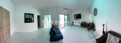 Spacious modern living room with sleek design and pool view, perfect for relaxation and entertainment.