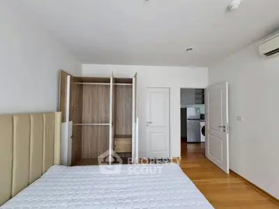 Spacious bedroom with wooden flooring and built-in wardrobe, featuring modern air conditioning.