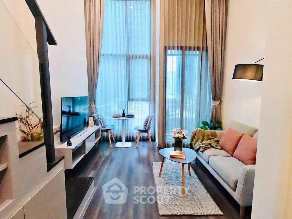 Modern living room with high ceilings, large windows, and stylish decor in a contemporary apartment.