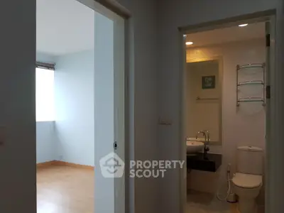 Modern apartment interior with bathroom and adjacent room, showcasing sleek design and natural lighting.