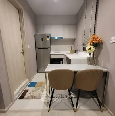 Modern compact kitchen with sleek design and cozy dining area, featuring stainless steel appliances and elegant decor.