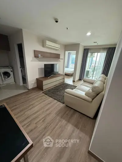 Modern living room with sleek furniture and wooden flooring, featuring a cozy atmosphere and natural light.