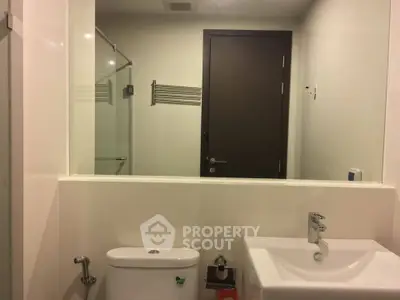 Modern bathroom with sleek fixtures and large mirror in a contemporary apartment.