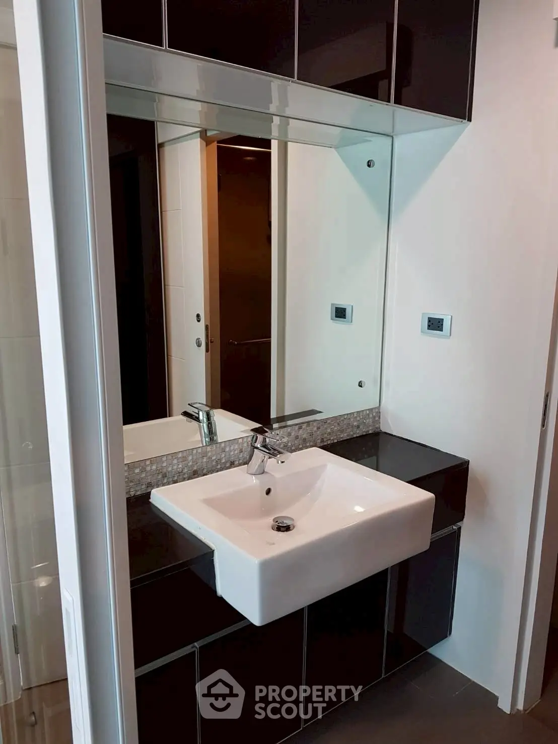 Modern bathroom with sleek sink and large mirror in contemporary apartment.