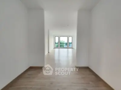 Spacious modern living room with large windows and wooden flooring.