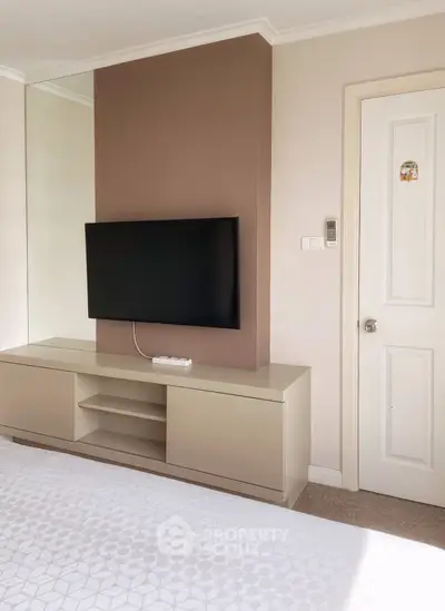 Modern bedroom with wall-mounted TV and sleek storage unit