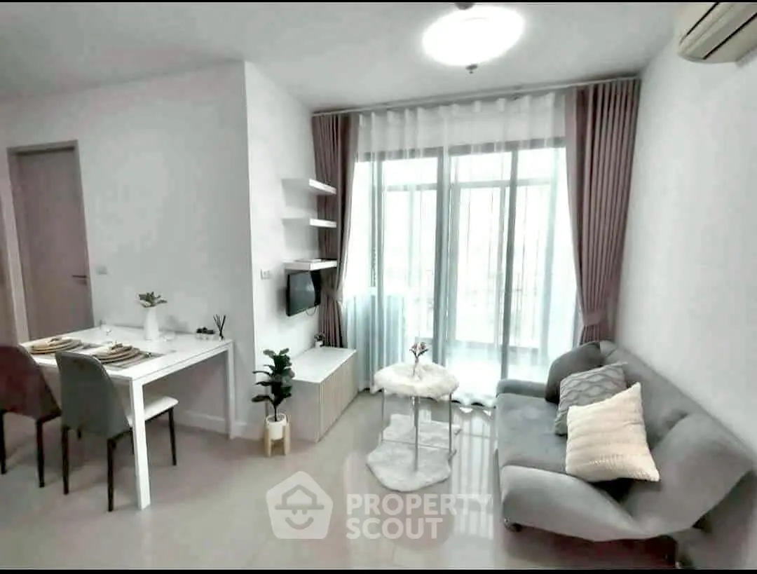 Modern living room with cozy sofa and dining area, featuring large windows and stylish decor.