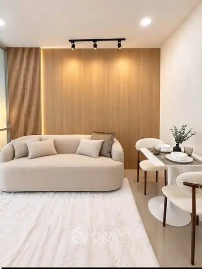 Modern living room with stylish sofa and dining area, featuring elegant lighting and contemporary decor.