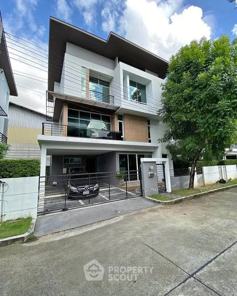 Modern three-story house with sleek design and spacious driveway in a serene neighborhood.