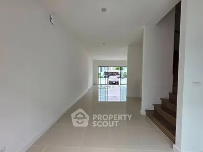 Spacious modern interior with tiled flooring and staircase, ideal for customization.