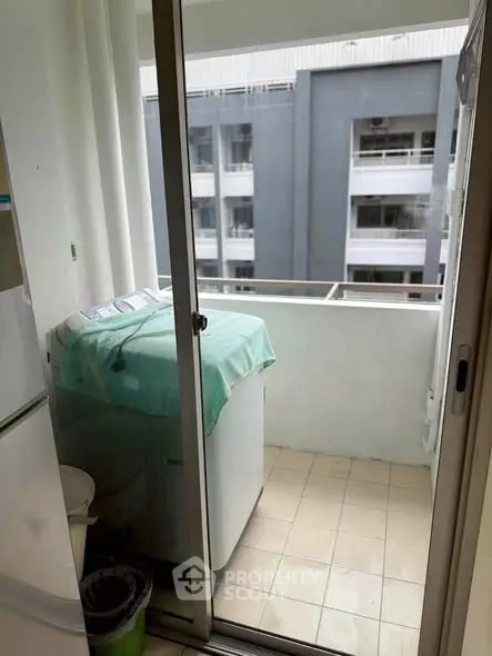 Compact balcony with washing machine and city view, ideal for urban living convenience.
