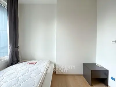 Minimalist bedroom with single bed and wooden nightstand, perfect for cozy living.