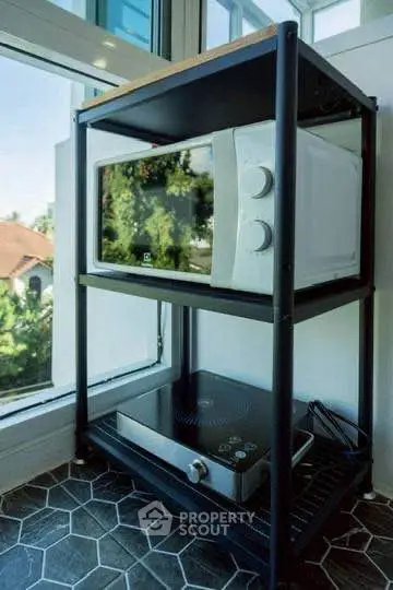 Modern kitchen corner with microwave and induction cooktop on sleek shelving unit.