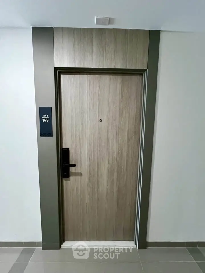 Modern apartment entrance with sleek wooden door and electronic lock system.