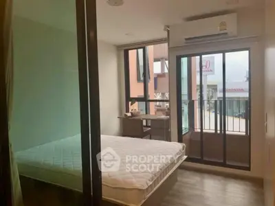 Modern bedroom with balcony access and natural light, featuring a minimalist design and air conditioning.