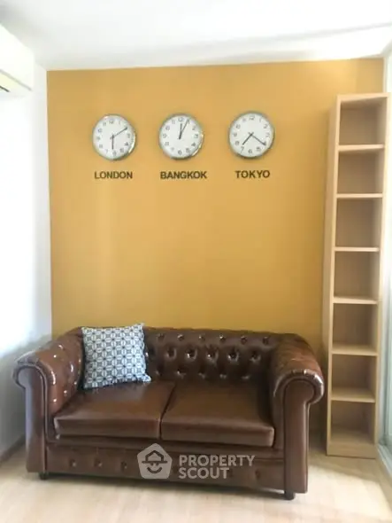 Stylish living room with leather sofa and world clocks on mustard wall, perfect for modern urban living.