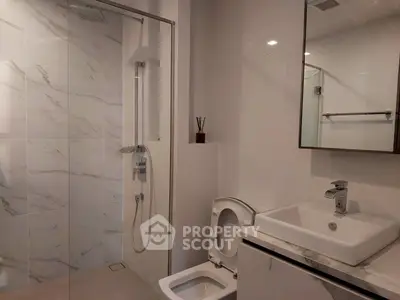Modern bathroom with sleek design, featuring a glass shower and elegant fixtures.