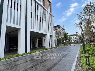Modern building exterior with landscaped entrance and clear blue sky.