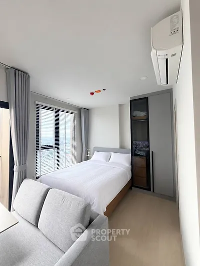 Modern bedroom with city view, featuring sleek design and ample natural light.