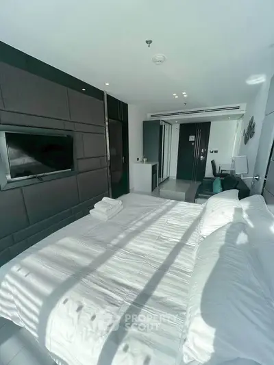 Modern bedroom with sleek design and natural light, featuring a wall-mounted TV and stylish decor.