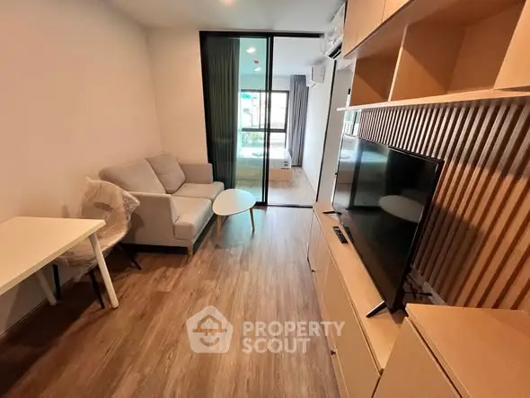 Modern living room with wooden flooring, cozy sofa, and large TV unit in a stylish apartment.