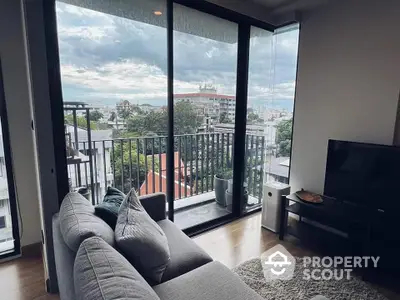 Modern living room with plush sofa and expansive windows offering a panoramic city view, leading to a cozy balcony, perfect for urban living.