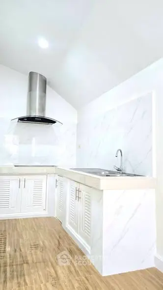 Modern kitchen with sleek white cabinetry and stainless steel range hood
