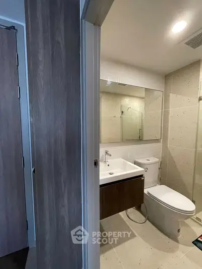 Modern bathroom with sleek fixtures and large mirror in contemporary apartment.