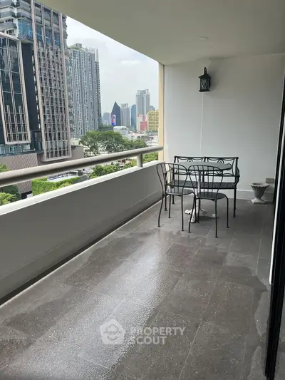 Spacious balcony with city view and elegant outdoor seating in modern high-rise apartment.