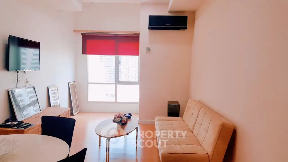 Modern living room with stylish furniture and large window offering city views.