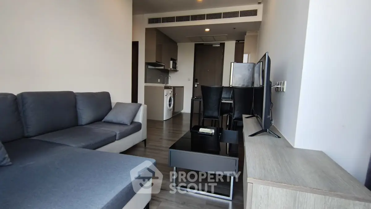 Modern living room with sleek furniture and open kitchen layout in a stylish apartment.