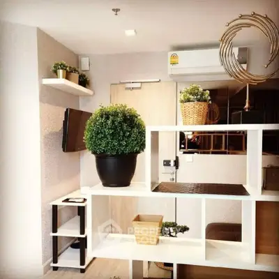 Modern living room with stylish shelving and indoor plants, featuring a wall-mounted TV and air conditioning.