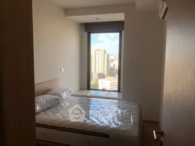 Modern bedroom with city view and natural light, featuring a comfortable bed and minimalist design.