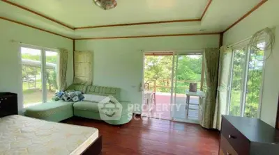 Spacious bedroom with large windows and access to a scenic balcony, offering serene views and natural light.