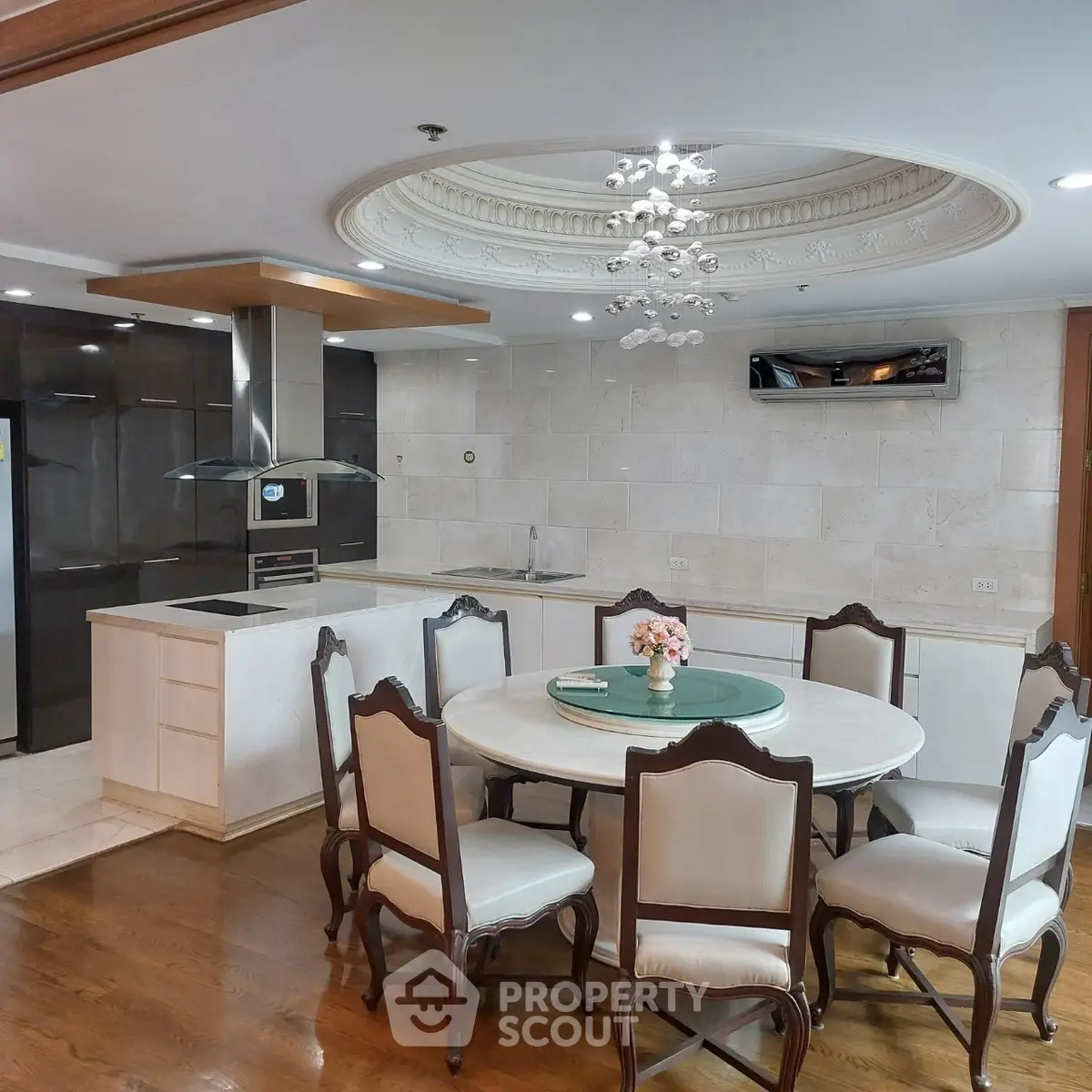 Elegant dining area with round table and chairs, adjacent to a modern kitchen with sleek appliances.