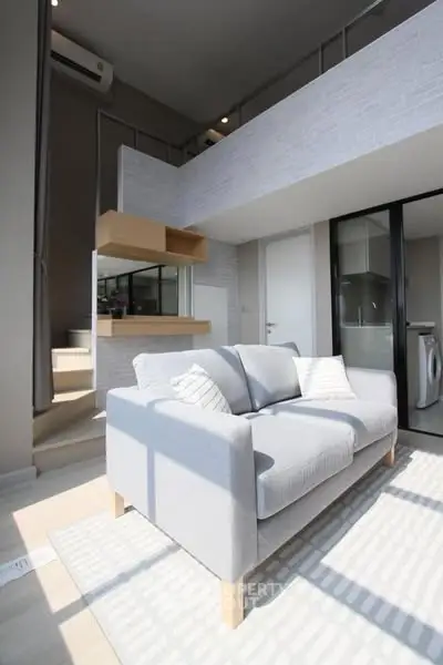 Modern loft-style living room with high ceiling and natural light
