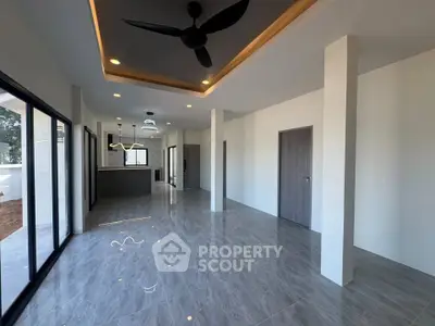 Spacious modern living room with sleek flooring and ceiling fan, perfect for contemporary living.