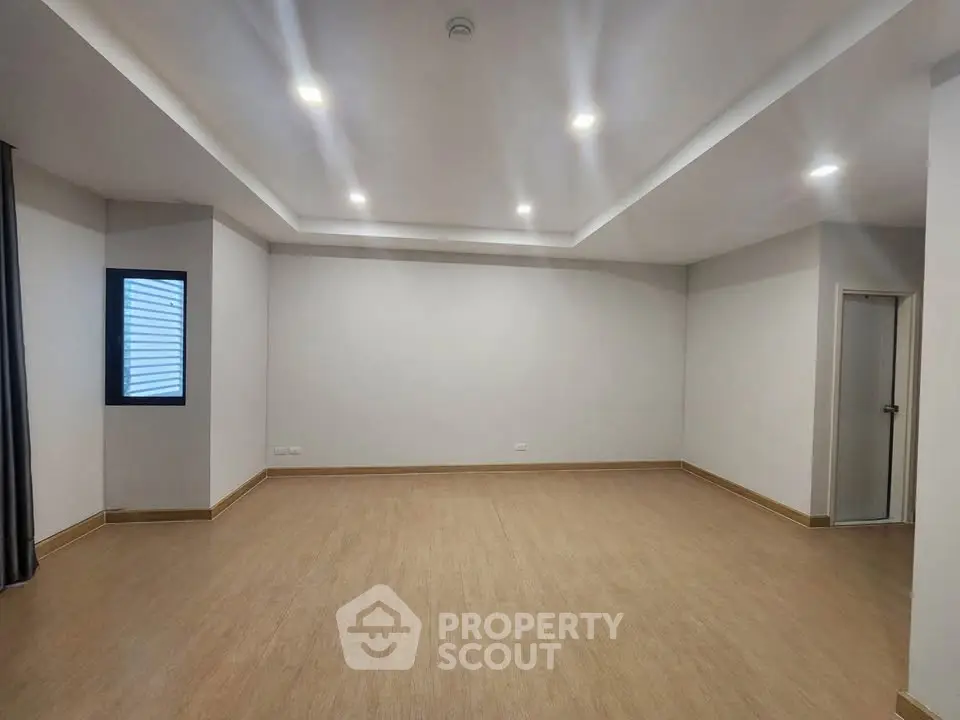 Spacious empty room with modern lighting and wooden flooring, ideal for customization.