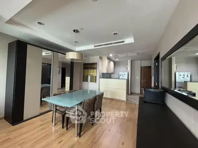 Spacious modern apartment with open layout connecting a sleek kitchen to an elegant dining area, featuring hardwood floors and contemporary lighting.
