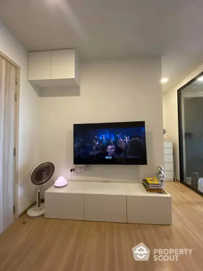 Modern living room with wall-mounted TV and sleek wooden flooring