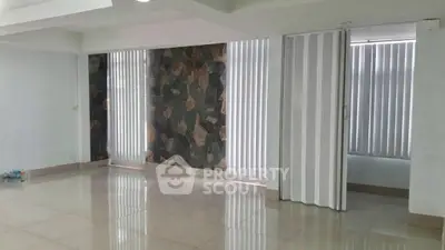 Spacious empty room with tiled flooring and vertical blinds, ideal for customization.