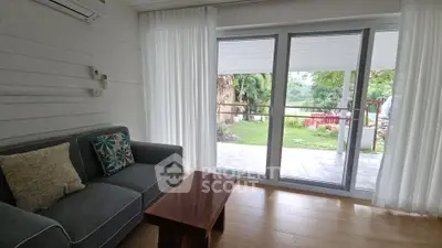 Charming living room with garden view, featuring cozy sofa and elegant wooden table, perfect for relaxation.