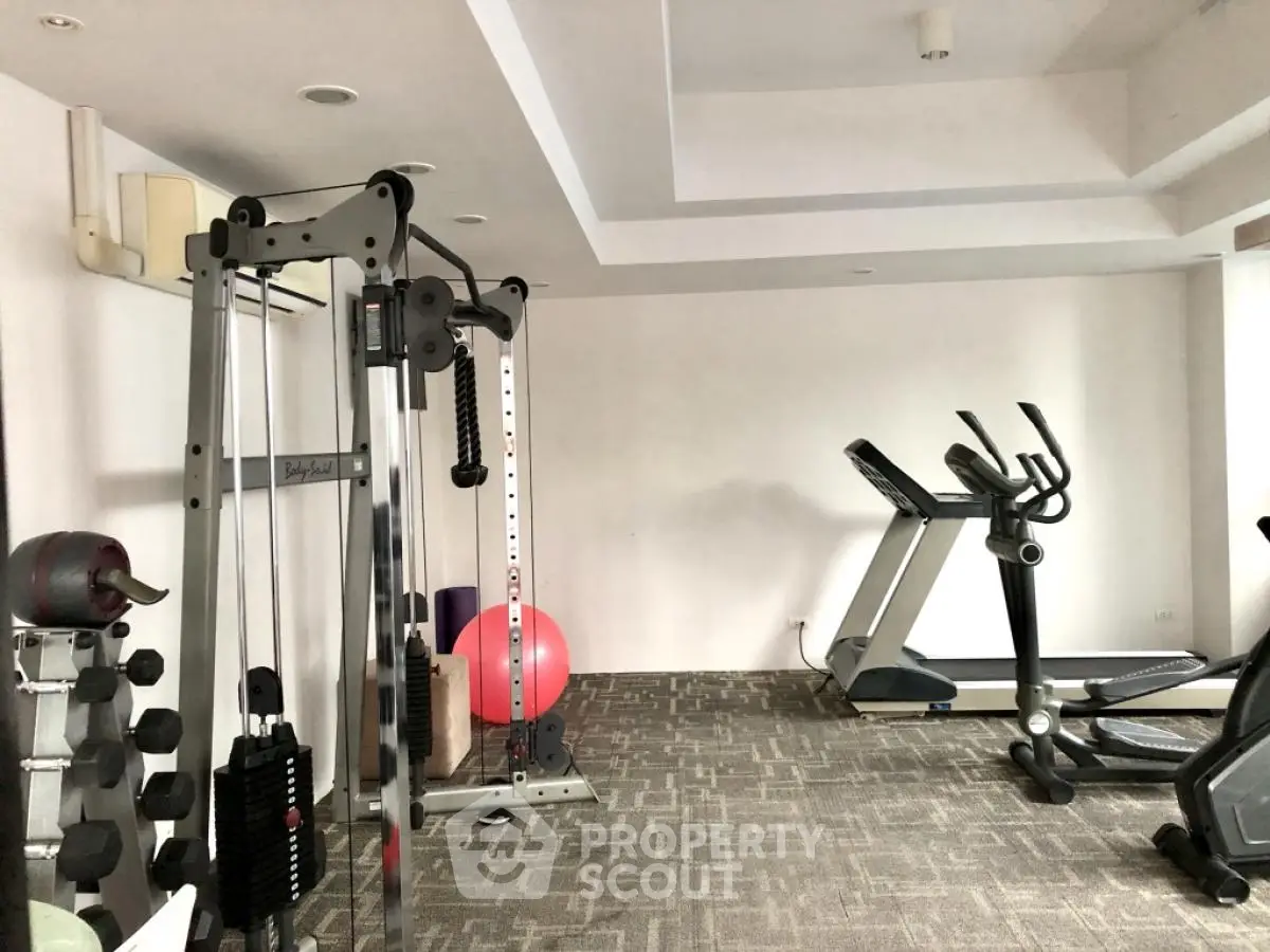 Modern home gym with exercise equipment and carpet flooring