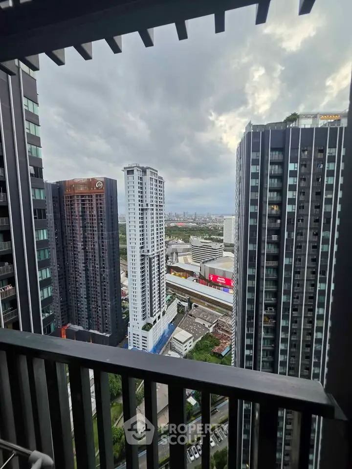 Stunning cityscape view from a high-rise balcony with modern skyscrapers and cloudy sky.