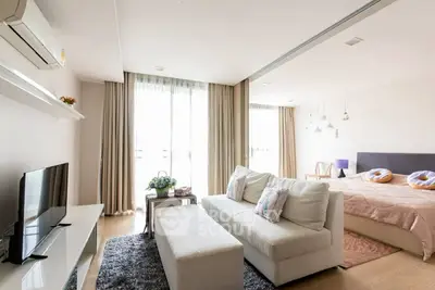Modern open-plan living room and bedroom with stylish decor and natural light